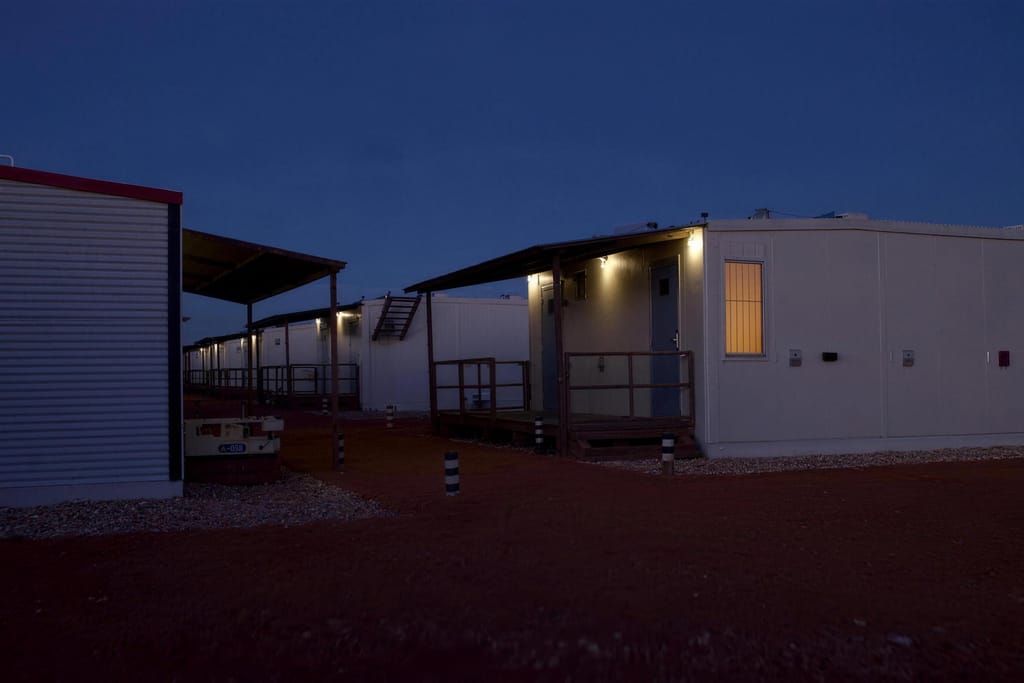 Accommodation units at a work camp at dusk with the walkway lights on