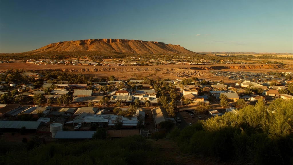 A wide view over a Pilbara town with a flat topped range behind it in late afternoon light