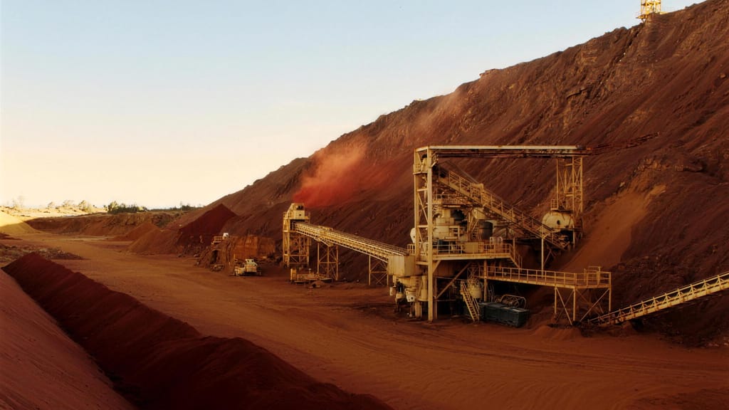A crushing plant and conveyors below a red waste dump