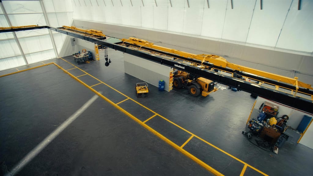 A gantry crane running the length of a workshop above a marked concrete floor