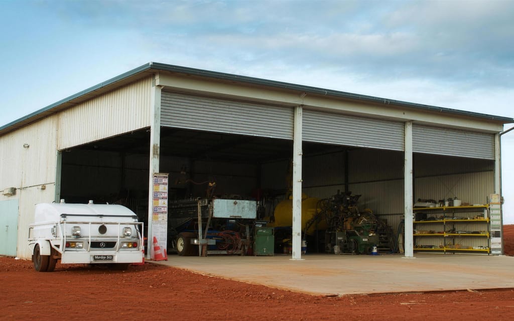 An open workshop shed with plant inside and a water truck parked on the hardstand